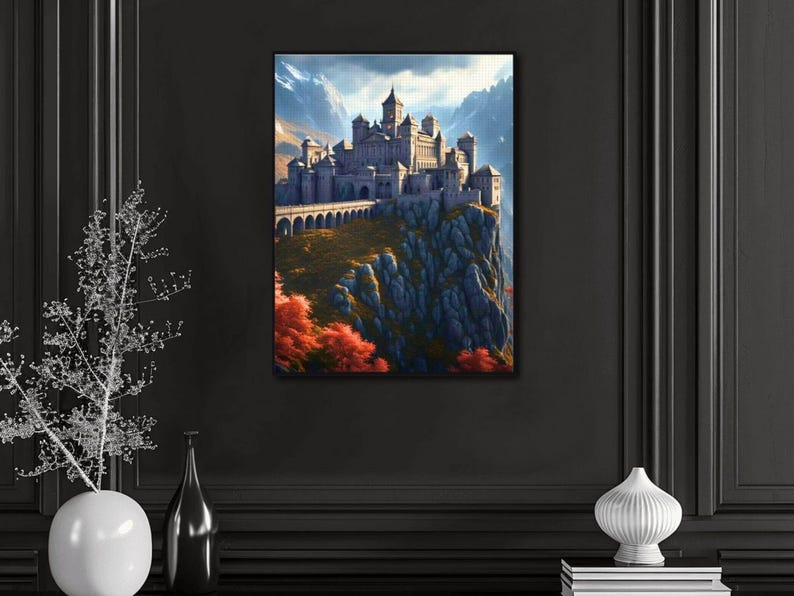 May include: A framed canvas print of a castle perched atop a rocky cliff, with a bridge leading to the castle. The artwork features a mountain backdrop and autumn-colored trees. The castle is gray, and the sky is blue.