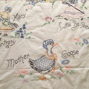 May include: Embroidered nursery rhyme tablecloth featuring Mary, Quite Contrary, Little Bo Peep, and a goose. The tablecloth is white with colorful embroidery.