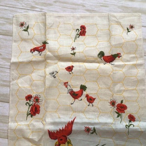 May include: A white tea towel with a yellow honeycomb pattern and red and white chickens and flowers.