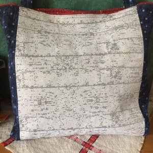 Pu&ograve; includere: Una borsa tote bianca con un motivo a stelle blu e bianche sui lati. La borsa &egrave; realizzata in tessuto intrecciato e ha una striscia rossa e bianca in alto.
