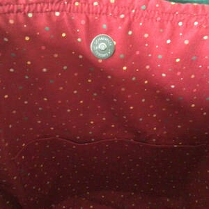 Pu&ograve; includere: L'interno di una borsa tote rossa con una piccola tasca e un motivo a pois bianchi. La borsa ha una chiusura a scatto in metallo argentato.