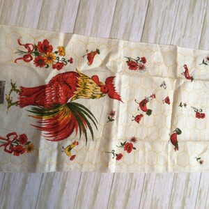 May include: A vintage kitchen towel with a red rooster and yellow chicks on a white background with a honeycomb pattern. The towel has red flowers and green leaves. The text "All Pure Linen" is printed on the towel.