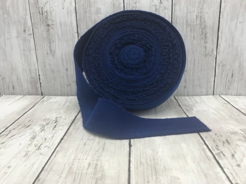 Peut inclure: Un rouleau de ruban en tissu bleu fonc&eacute;. Le ruban est enroul&eacute; et l'extr&eacute;mit&eacute; est d&eacute;roul&eacute;e.