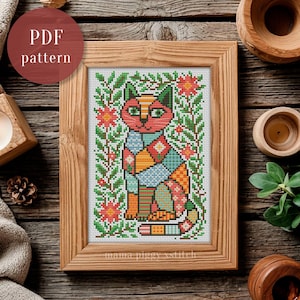 May include: A cross stitch pattern featuring a stylized cat composed of geometric shapes in shades of red, orange, blue, and green, surrounded by floral and leaf motifs. The design is displayed in a wooden frame with the text PDF pattern.