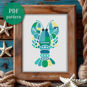 May include: A framed cross-stitch pattern of a lobster in shades of blue, green, and yellow. The artwork is in a wooden frame and includes the text "PDF pattern" and "mama piggy xstitch". The background includes starfish and rope.