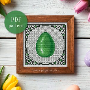 May include: A framed cross-stitch pattern with a green egg design, set within a geometric border and a wooden frame. The words "PDF pattern" are in a green circle. The text "mama piggy xstitch" is at the bottom of the frame.