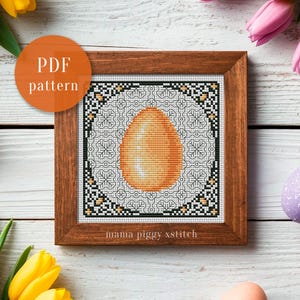Può includere: Un modello a punto croce incorniciato con un disegno a uovo dorato. Il motivo è circondato da un bordo geometrico in bianco, nero e verde. Il testo "PDF pattern" è in un cerchio arancione. Il testo "mama piggy xstitch" è in basso.