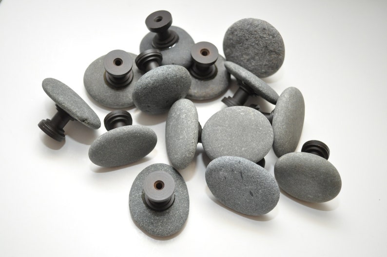 Peut inclure: Un ensemble de boutons de porte en pierre grise avec des ferrures en m&eacute;tal noir. Les boutons sont de forme ovale et ont une texture rugueuse et naturelle.