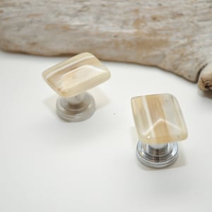 May include: Two decorative cabinet knobs with a white and brown striped design. The knobs have a chrome base.