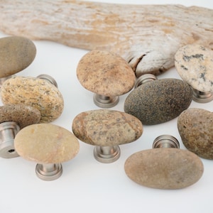 May include: A set of ten natural stone cabinet knobs with silver metal bases. The knobs are various shades of brown and gray, with some having a speckled pattern.