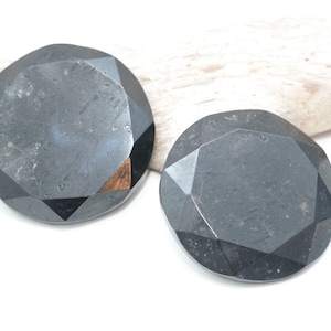 May include: Two black faceted round buttons with a shiny finish.