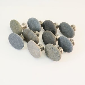 May include: Ten oval-shaped natural stone drawer pulls with silver metal hardware. The stones are various shades of gray and brown.