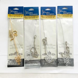 May include: Four fan pull assemblies in clear packaging. Each package has a blue header with the text "Jewelry Designer." The pulls have decorative designs, including a gold-toned swirl and silver-toned shapes. The text "Make Your Own FAN PULL!" is visible.