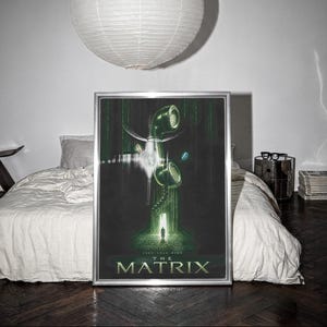 May include: A framed movie poster for The Matrix featuring a green digital rain background, a vintage telephone handset, a small silhouette of a person standing in a doorway, and the text The Matrix printed in large white letters at the bottom.