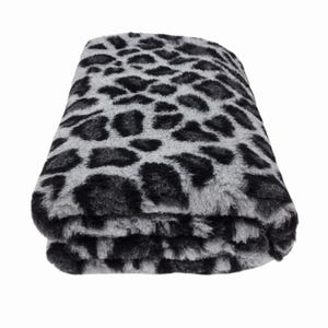 May include: Folded plush blanket with a grey and black leopard print pattern. The blanket is made of a soft, furry material and is folded neatly, showcasing the animal print design. The blanket is a neutral colour and can be used as a throw.