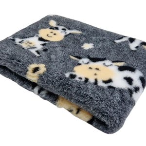 May include: A soft, grey pet bed with a black and white cow print. The bed is made of plush fabric and has a comfortable, cosy feel.