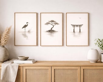 Könnte beinhalten: Drei gerahmte Kunstdrucke mit minimalistischem japanischem Thema. Die Drucke zeigen einen Reiher im Wasser, einen Bonsai-Baum und ein Torii-Tor. Das Kunstwerk ist in Graustufen gehalten und hat einen natürlichen Holzrahmen. Die Drucke werden über einem Holzschrank ausgestellt.