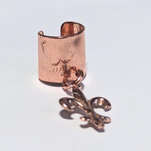 Puño para la oreja con diseño de flor de lis