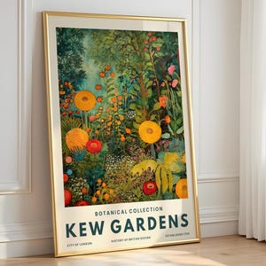 May include: A framed print of Kew Gardens, showcasing a colourful botanical illustration with orange and red flowers, and green foliage. The print is in a gold frame and leans against a white wall. The text "Kew Gardens" is visible.