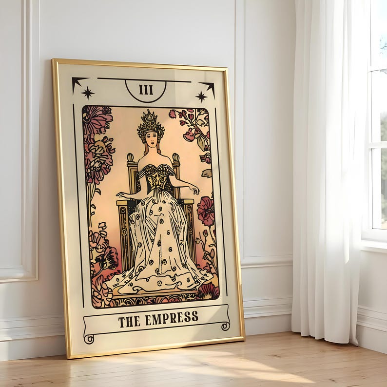 May include: A framed tarot card print featuring "The Empress." The artwork depicts a woman in a gown seated on a throne, surrounded by floral elements. The frame is gold-colored, and the overall design has a vintage aesthetic.