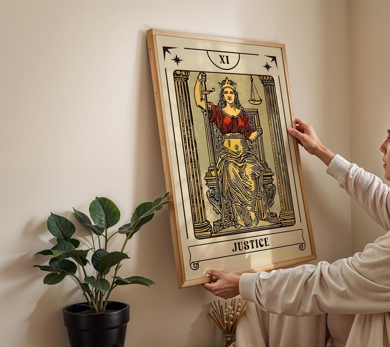 K&ouml;nnte beinhalten: Ein gerahmter Wandkunstdruck, der die Tarotkarte Gerechtigkeit mit der Beschriftung XI zeigt. Die Illustration stellt eine gekr&ouml;nte Figur dar, die zwischen zwei S&auml;ulen sitzt, ein Schwert in der einen und eine Waage in der anderen Hand h&auml;lt.