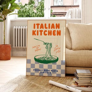 May include: A vintage-style poster advertising an Italian kitchen. The poster features a blue and white checkered background with the text "ITALIAN KITCHEN" in orange and green. The poster also features a drawing of a bowl of pasta with the text "Pasta is my love language" and "La Dolce Vita" in cursive.