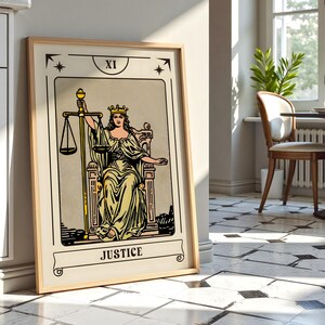 May include: A framed tarot card print of the Justice card. The artwork features a woman in a yellow gown holding scales and a sword, seated on a throne. The card is labeled "XI" at the top and "JUSTICE" at the bottom, with a beige background.