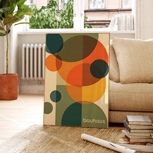 Pu&ograve; includere: Stampa d'arte geometrica astratta con cerchi sovrapposti in tonalit&agrave; di arancione, giallo, verde e marrone. La stampa ha la parola "bauhaus" in basso.