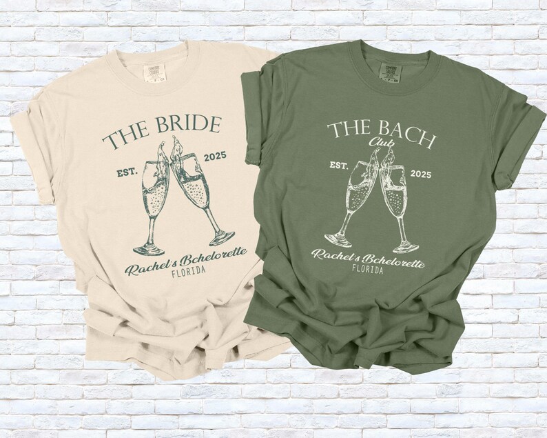 Pu&ograve; includere: Due magliette, una color crema e una verde oliva, con grafiche abbinate. La maglietta color crema dice "The Bride" con calici di champagne e "Rachel's Bachelorette, Florida". La maglietta verde dice "The Bach Club" con calici di champagne e "Rachel's Bachelorette, Florida".