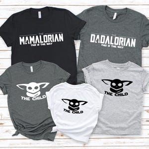 May include: A collection of five t-shirts with white text on various colors. The shirts feature the phrases "The Mamalorian", "The Dadalorian", and "The Child". The text "This is the Way" is below "The Mamalorian" and "The Dadalorian".