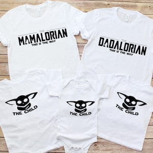 May include: White t-shirts with black text. The shirts read "The Mamalorian" and "The Dadalorian" with "This is the Way" underneath. Other shirts and a onesie feature "The Child" graphic.