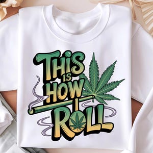 May include: White sweatshirt featuring a green cannabis leaf and the text "This is how I roll" in colourful, stylised lettering.
