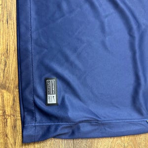 May include: A navy blue t-shirt with a white Nike logo and the text "AUTHENTIC" and "2017" in white. The text "1328853" is also in white.