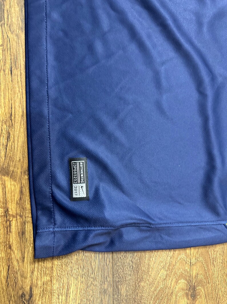 May include: A navy blue t-shirt with a white Nike logo and the text "AUTHENTIC" and "2017" in white. The text "1328853" is also in white.