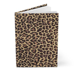 May include: A brown and black leopard print journal with a white spine.