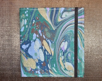 May include: A green, blue and gold marbled notebook cover with a black elastic band closure.