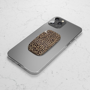 May include: A leopard print phone charger sits on top of a silver smartphone.