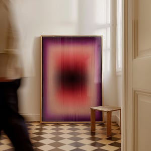 Op de afbeelding: Een rechthoekig ingelijst kunstwerk aan de muur met een verticaal verloop van dieppaars, helderrood en een centrale zwarte kern. Het kunstwerk heeft een wazige, lineaire textuur door de kleurovergang en zit in een dunne, lichtgekleurde lijst.