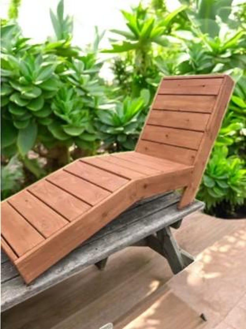 May include: A wooden lounge chair with a slatted design. The chair is made of natural wood and has a rustic look. It is perfect for relaxing outdoors.