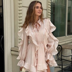 K&ouml;nnte beinhalten: Eine wei&szlig;e Keramik-Tasse mit schwarzem Henkel und dem Text "But First, Coffee" in schwarzer, handschriftlicher Schrift. Die Tasse steht auf einer wei&szlig;en Oberfl&auml;che.