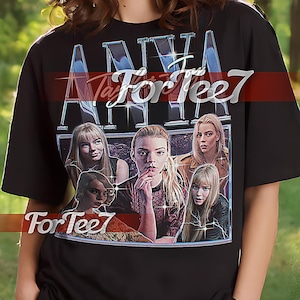 Puede incluir: Camiseta unisex negra con un gráfico de la palabra "ANNA" en una fuente estilizada, con imágenes de mujeres. La camiseta también tiene el texto "For Tee7". La modelo lleva una camiseta XL.