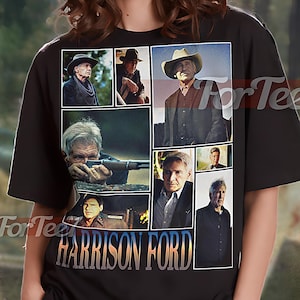 May include: Black unisex t-shirt featuring a collage of Harrison Ford images. The shirt includes the text "HARRISON FORD" in a stylized font. The shirt is worn by a person.