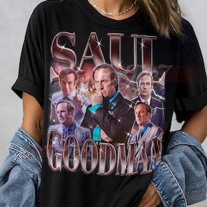 Peut inclure: T-shirt unisexe noir avec un graphisme de Saul Goodman et le texte "SAUL GOODMAN". Le design comprend plusieurs images du personnage. Le t-shirt est de style col rond classique.