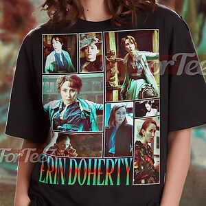 Könnte beinhalten: Schwarzes Unisex-T-Shirt mit einer Collage von Bildern und dem Namen "ERIN DOHERTY" in farbigem Text. Das Shirt hat oben die Aufschrift "UNISEX SHIRT". Das Model trägt ein XL-Shirt.