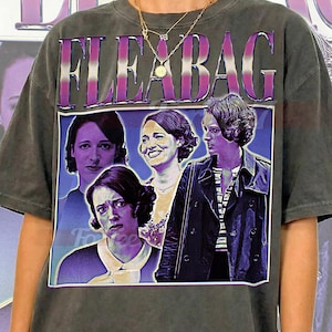 May include: Dark gray unisex t-shirt featuring the word "FLEABAG" in purple and white block letters above a collage of four images of a woman. The shirt has a vintage, worn look. The text "UNISEX SHIRT" is at the top.