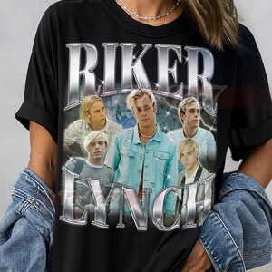 Peut inclure: T-shirt unisexe noir avec un graphisme du groupe Riker Lynch. Le design comprend le nom du groupe dans une police argentée et métallique. Le t-shirt est de style col rond classique.