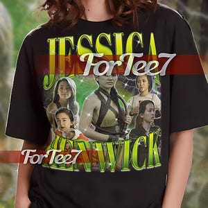 Può includere: Maglietta unisex nera con una stampa grafica di un viso femminile con il testo "JESSICA For Tee7 WICK" in giallo.