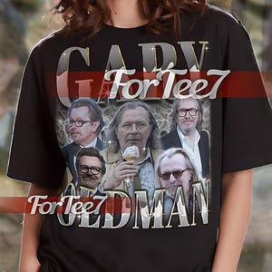 Puede incluir: Camiseta unisex negra con un estampado gráfico de una banda llamada "Gary Oldman" con el texto "For Tee7" en la camiseta. La modelo lleva una talla XL.