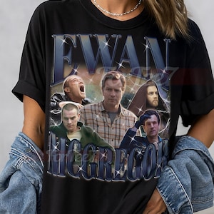 Puede incluir: Camiseta unisex negra con un gráfico de Ewan McGregor y el texto "EWAN MCGREGOR". El diseño tiene un estilo vintage, con múltiples imágenes del actor. La camiseta está hecha de un material suave.