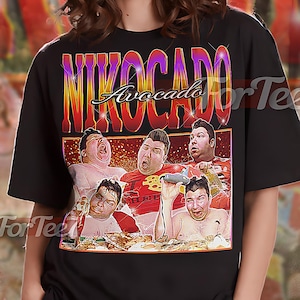 Könnte beinhalten: Schwarzes Unisex-T-Shirt mit einem Retro-Grafik des Wortes "NIKOCADO" und einem Bild einer Person. Das Shirt hat das Wort "Avocado" über dem Bild. Das T-Shirt ist ein Unisex-Stil.